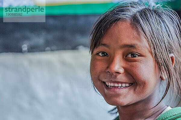 Dolpo  Nepal  ca. Mai 2012: Junges braunhaariges Mädchen lächelt freundlich in die Fotokamera mit braunen glitzernden Augen in Dolpo  Nepal. Dokumentarischer Leitartikel  Asien