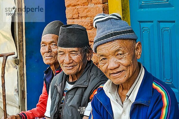 Beni  Nepal  ca. Mai 2012: Drei alte Männer mit Mützen auf dem Kopf sitzen auf einer Bank und lächeln in die Fotokamera in Beni  Nepal. Dokumentarischer Leitartikel  Asien