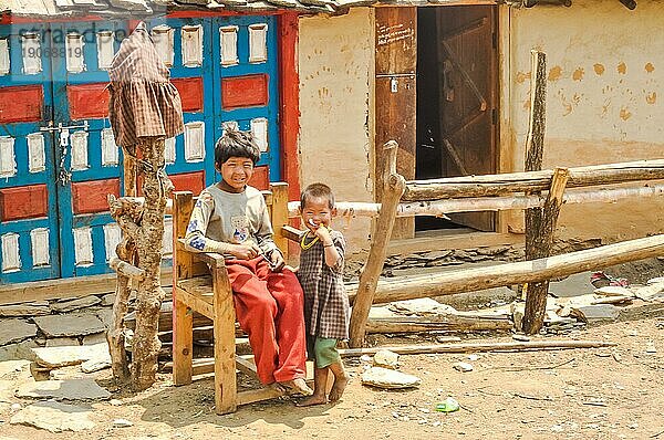 Dolpo  Nepal  etwa im Mai 2012: Junge einheimische Kinder spielen draußen und schauen neugierig in die Fotokamera in Dolpo  Nepal. Ein älteres sitzt auf einem Holzstuhl. Dokumentarischer Leitartikel  Asien
