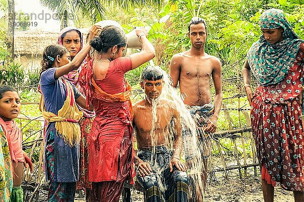 Paigacha  Bangladesch  etwa im Juli 2012: Junge einheimische Mädchen und Jungen stehen halbnackt im Schlamm in Paigacha  Bangladesch. Im Hintergrund schöne Grünanlagen und Häuser. Dokumentarischer Leitartikel  Asien