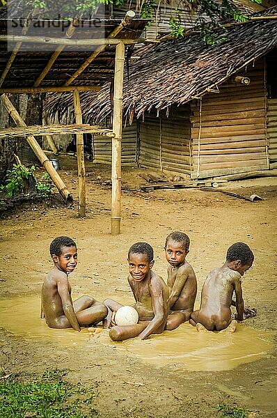 Will will  Nuku  Papua Neuguinea  Juli 2015: Vier nackte Jungen spielen im Schlamm und lächeln in die Fotokamera in Will will in Nuku  Papua Neuguinea. In dieser Region trifft man nur auf Menschen aus isolierten lokalen Stämmen. Dokumentarischer Leitartikel