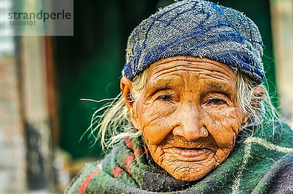 Beni  Nepal  ca. Mai 2012: Foto einer alten Frau mit Falten und Piercing  die eine blaue Mütze trägt und in den Straßen von Beni  in die Kamera schaut. Dokumentarischer Leitartikel  Asien