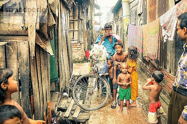 Khulna  Bangladesch  etwa im Juli 2012: Einheimischer Mann in blauem TShirt und kleine Kinder posieren mit Fahrrad in einer engen Gasse im Slum von Khula  Bangladesch. Dokumentarischer Leitartikel  Asien