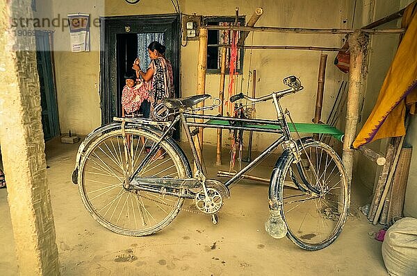 Srimongal  Bangladesch  etwa im Juli 2012: Foto eines alten schwarzen Fahrrads in einem Unterstand in Srimongal  Bangladesch. Im Hintergrund eine Frau und ein kleines Kind. Dokumentarischer Leitartikel  Asien