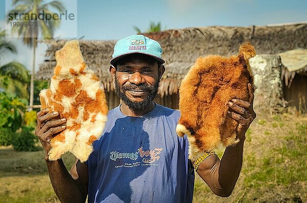 Will will  Nuku  Papua Neuguinea  Juli 2015: Ein Eingeborener mit blaür Mütze hält ein Fell von toten Tieren und lächelt in die Kamera in Will will  Papua Neuguinea. Dokumentarischer Leitartikel