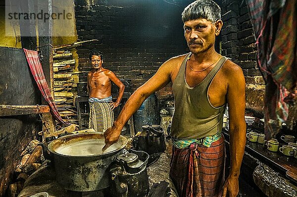 Chittagong  Bangladesch  etwa im Juli 2012: Einheimischer Mann rührt Essen in einem Topf in der Küche eines ländlichen Dorfes in der Nähe von Chittagong  Bangladesch. Im Hintergrund ein halbnackter Mann. Dokumentarischer Leitartikel  Asien