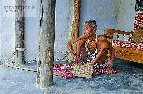 Srimongal  Bangladesch  etwa im Juli 2012: Alter dünner Mann sitzt auf einer karierten Decke auf dem Boden und schaut nach links in Srimongal  Bangladesch. Dokumentarischer Leitartikel  Asien