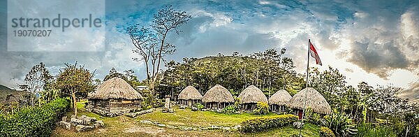 Panoramablick auf eine Reihe traditioneller Häuser mit Strohdächern in einem Dorf mit Fahne im Dani Kreis in der Nähe von Wamena  Papua  Indonesien  Asien