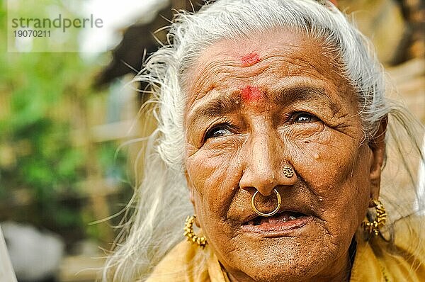 Damak  Nepal  ca. Mai 2012: Eine alte Frau mit roten Punkten auf der Stirn und goldenen Piercings in der Nase blickt zum nepalesischen Flüchtlingslager in Damak  Nepal. Dokumentarischer Leitartikel  Asien