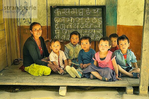 Kanchenjunga Trek  Nepal  etwa im Mai 2012: Lehrer sitzt mit Kindern auf dem Boden und sie posieren für die Fotokamera in Kanchenjunga Trek  Nepal. Dokumentarischer Leitartikel  Asien