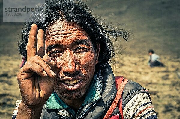 Dolpo  Nepal  ca. Juni 2012: Ein einheimischer schwarzhaariger Mann trägt eine Jacke mit erhobener Hand als Symbol des Friedens in Dolpo  Nepal. Dokumentarischer Leitartikel  Asien
