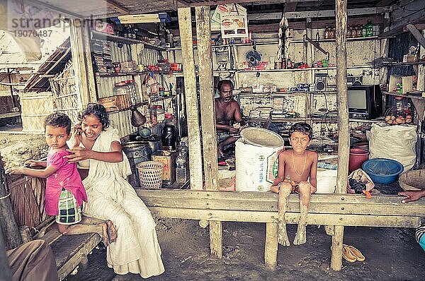 Sunderban  Bangladesch  ca. Juli 2012: Eine einheimische Familie sitzt in ihrem Haus und die barfuß lebenden Kinder blicken in Sunderban  in die Fotokamera. Dokumentarischer Leitartikel  Asien