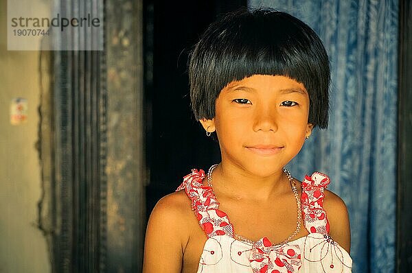 Srimongal  Bangladesch  ca. Juli 2012: Ein junges Mädchen mit kurzen schwarzen Haaren in einem weiß roten Kleid lächelt freundlich in die Kamera in Srimongal  Bangladesch. Dokumentarischer Leitartikel  Asien