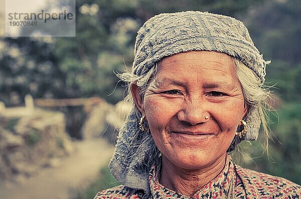 Beni  Nepal  ca. Mai 2012: Einheimische grauhaarige Frau mit Kopftuch und goldenen Ohrringen und Piercing lächelt freundlich in die Fotokamera in Beni  Nepal. Dokumentarischer Leitartikel  Asien