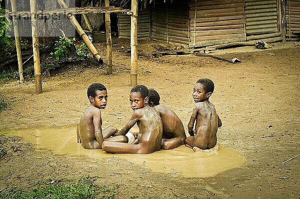 Will will  Nuku  Papua Neuguinea  Juli 2015: Kleine nackte Jungen sitzen auf dem Boden und spielen im Schlamm in Will will in Nuku  Papua Neuguinea. In dieser Region trifft man nur Menschen von isolierten lokalen Stämmen. Dokumentarischer Leitartikel