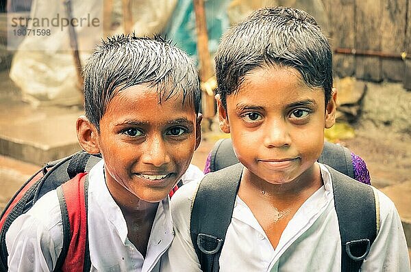 Khulna  Bangladesch  etwa im Juli 2012: Zwei Jungen in nasser weißer Kleidung und mit naßen Haaren stehen im Regen und lächeln in die Fotokamera auf der Straße im Slum von Khula  Bangladesch. Dokumentarischer Leitartikel  Asien