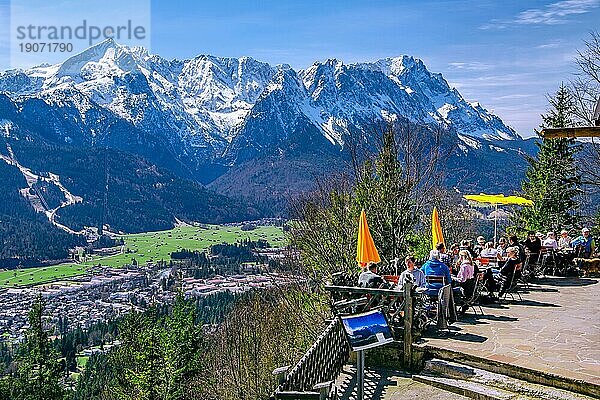 Sonnenterrasse der Martinshütte mit Aussicht auf das Tal  den Ort und die Zugspitzgruppe 2962m im Wettersteingebirge  Garmisch-Partenkirchen  Loisachtal  Werdenfelser Land  Bayerische Alpen  Oberbayern  Bayern  Deutschland  Europa