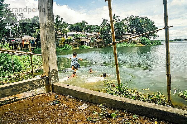 Rangamati  Bangladesch  ca. Juli 2012: Ein kleines Mädchen springt in den Fluss  um mit anderen Kindern zu schwimmen. Im Hintergrund sind Grünflächen und Häuser in Rangamati  Bangladesch. Dokumentarischer Leitartikel  Asien