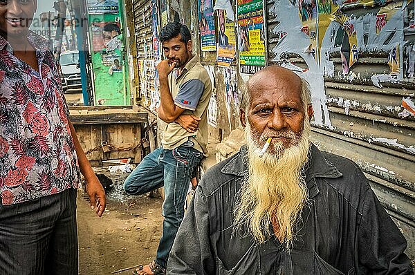 Dhaka  Bangladesch  ca. Juli 2012: Alter Mann mit Glatze und langem weißen Bart raucht eine Zigarette und blickt stirnrunzelnd in die Fotokamera auf der Straße in Dhaka  Bangladesch. Dokumentarischer Leitartikel  Asien