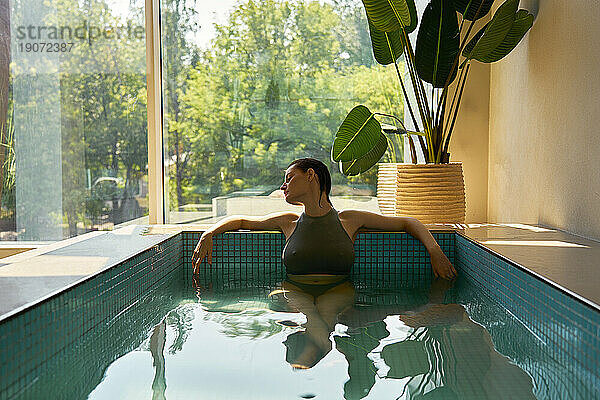 Woman with eyes closed relaxing in hot tub at spa