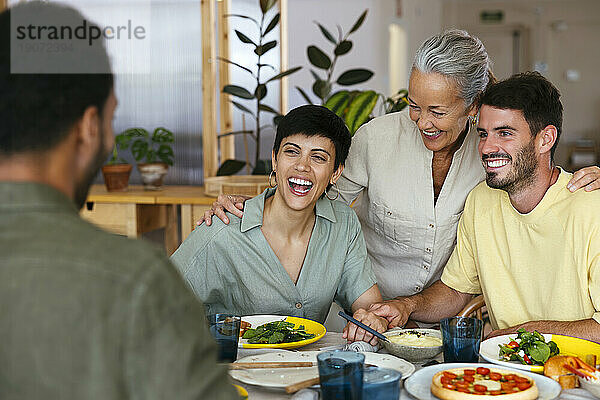 Glückliche Familie beim gemeinsamen Mittagessen am Esstisch in der Küche