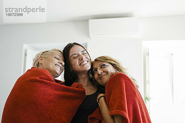 Fröhliche Freunde zusammen in Decke gehüllt in der Wohnung