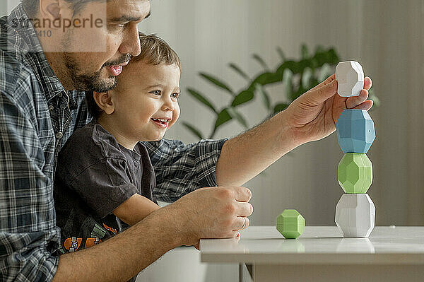 Vater und Sohn bauen zu Hause einen Turm aus Blöcken