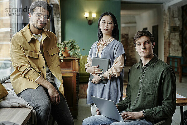 Lächelnde junge Geschäftskollegen mit Tablet-PC und Laptop im Café