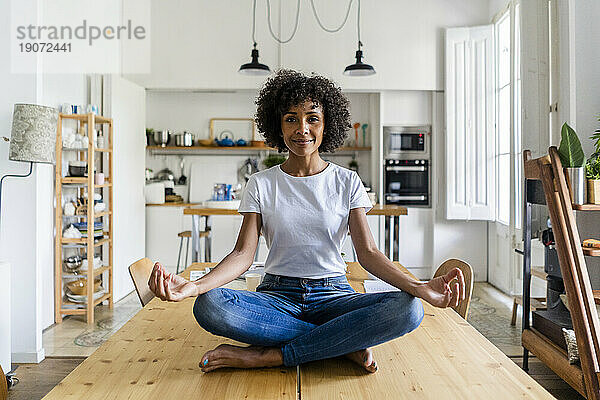 Porträt einer lächelnden Frau in Yoga-Pose auf dem Tisch zu Hause