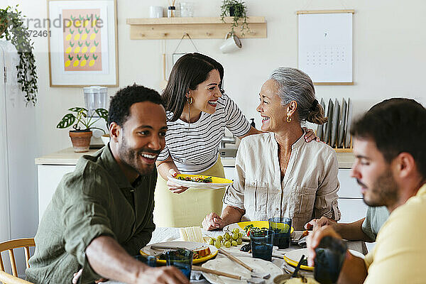 Glückliche Familie verbringt ihre Freizeit beim Mittagessen am Esstisch in der Küche