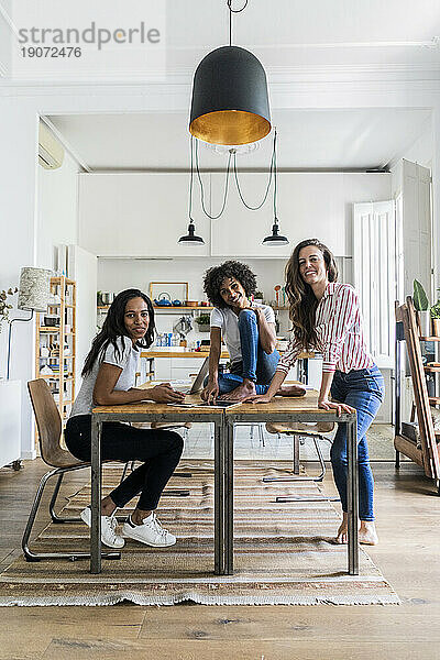 Porträt von drei glücklichen Frauen am Tisch zu Hause