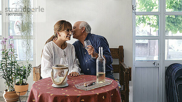 Glücklicher älterer Mann umarmt Frau  die im Restaurant sitzt