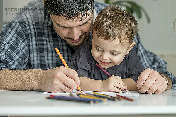 Father and son coloring together at home