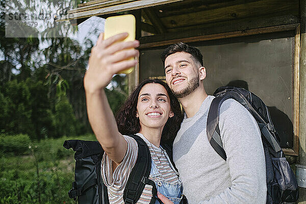 Lächelnde Frau macht ein Selfie mit ihrem Freund per Smartphone