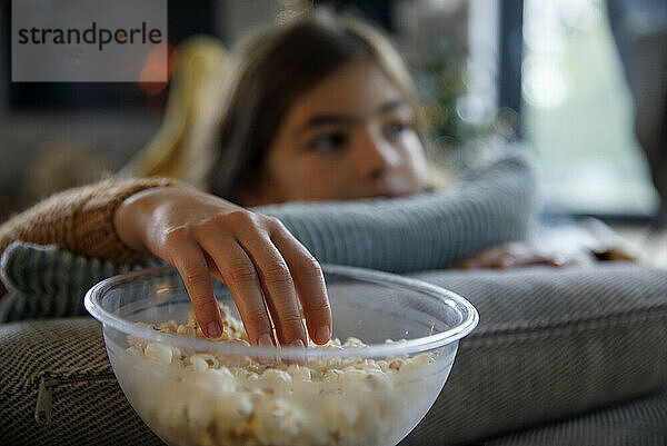 Mädchen isst zu Hause Popcorn aus einer Schüssel