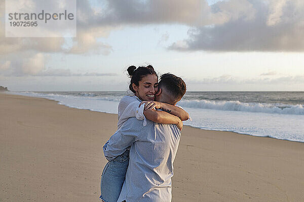Junger Mann umarmt Frau am Strand