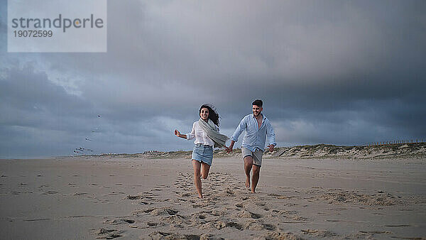 Glückliches junges Paar läuft zusammen am Strand
