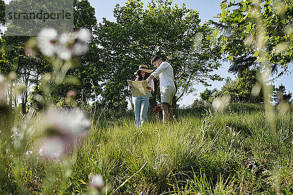Mann und Frau diskutieren über eine Karte  die auf Gras im Park steht