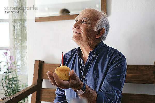 Lächelnder älterer Mann hält Cupcake
