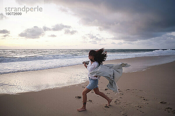 Sorglose Frau läuft am Strand auf Sand