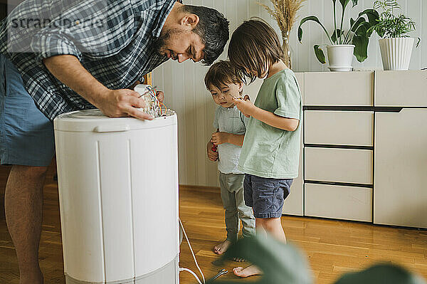 Vater repariert Waschmaschine mit Kindern zu Hause