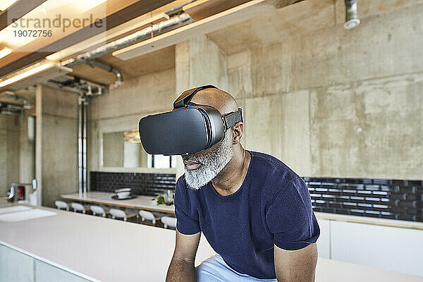 Reifer Geschäftsmann im modernen Büro mit VR-Brille