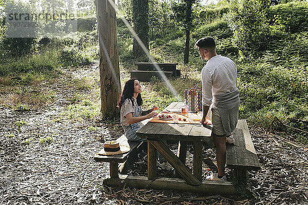 Junges Paar genießt Essen auf einer Bank im Wald