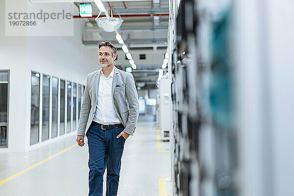 Confident businessman walking in a modern factory
