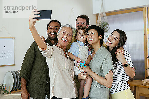 Fröhliche Familie macht Selfie mit Smartphone in der Küche