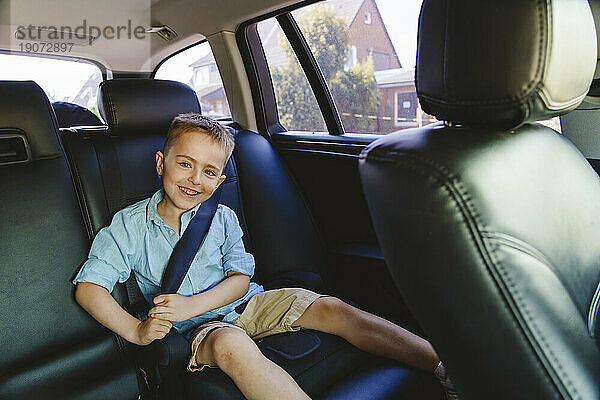 Lächelnder Junge mit Sicherheitsgurt im Auto