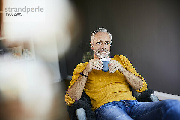 Entspannter reifer Mann zu Hause bei einer Tasse Kaffee