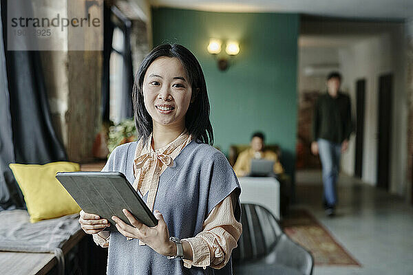Selbstbewusste junge Geschäftsfrau hält Tablet-PC im Café