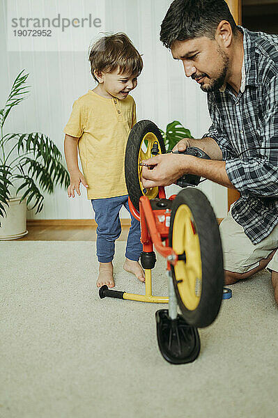 Vater repariert zu Hause das Fahrrad seines lächelnden Sohnes