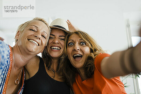 Fröhliche Frau macht Selfie mit Freunden in der Wohnung